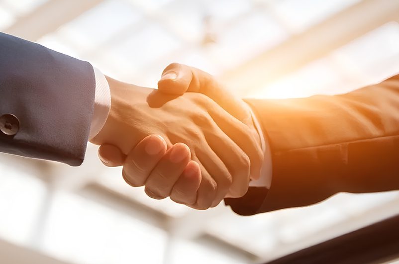 Two people shaking hands in a room.