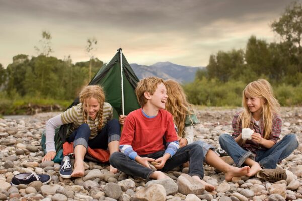 A group of kids sitting on the ground near some rocks