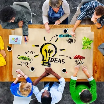 A group of people sitting around a table with an idea written on it.